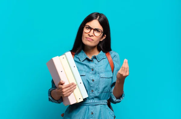 young hispanic student woman making capice or money gesture, telling you to pay your debts!