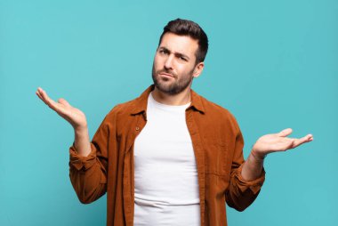 Yakışıklı, sarışın, kafası karışmış ve stresli görünen bir adam. Farklı seçenekler arasında merak ediyor. Belirsiz hissediyor.