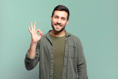 Yakışıklı yetişkin sarışın adam mutlu, rahat ve tatmin olmuş hissediyor. Onayını iyi bir hareketle gösteriyor. Gülümsüyor.