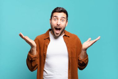 Yakışıklı sarışın adam mutlu, heyecanlı, şaşırmış ya da şok olmuş, gülümseyen ve hayrete düşmüş.