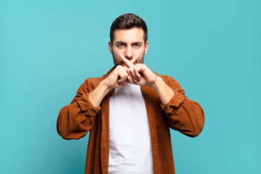 Yakışıklı sarışın adam ciddi görünüyor ve iki parmağının önde olması hoşnutsuzca reddedilerek sessizlik istiyor.