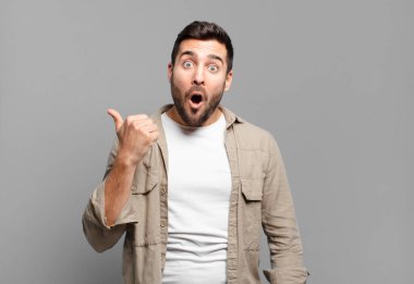 Yakışıklı sarışın adam, inanamadığı için hayrete düşmüş, yan taraftaki objeyi işaret ederek 