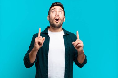 Yakışıklı, yetişkin, sarışın, korkan ve ağzı açık bir adam. Şok olmuş ve şaşırmış bir şekilde yukarı bakıyor.