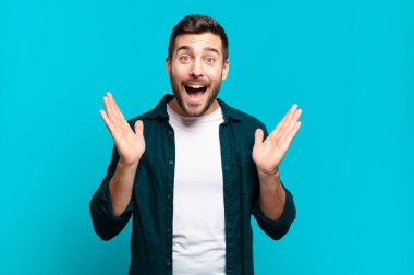 Yakışıklı sarışın adam mutlu ve heyecanlı görünüyor. Beklenmedik bir sürprizle şoke oldu. İki eli de açık.