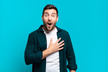 Yakışıklı, yetişkin sarışın bir adam şok olmuş ve şaşırmış hissediyor, gülümsüyor, el ele tutuşuyor, mutlu ya da şükran duyuyor.