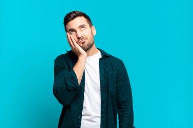 Yakışıklı, yetişkin sarışın bir adam yorgun, sıkıcı ve sıkıcı bir işten sonra sıkılmış, hayal kırıklığına uğramış ve uykulu hisseder.