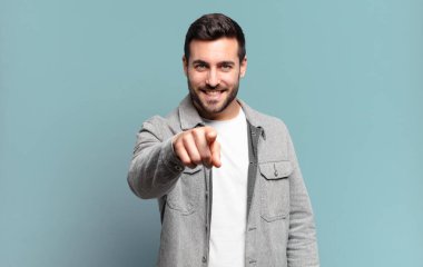 Yakışıklı, yetişkin, sarışın bir adam kameraya bakıyor. Tatmin olmuş, kendine güvenen, dost canlısı bir gülümsemeyle, seni seçiyor.