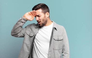 Yakışıklı sarışın adam stresli, yorgun ve hayal kırıklığına uğramış görünüyor, alnından ter akıyor, umutsuz ve bitkin hissediyor.