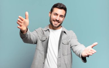 Yakışıklı, yetişkin, sarışın bir adam neşeyle gülümsüyor sıcak, dostça, sevgi dolu bir kucaklama yapıyor, mutlu ve sevimli hissediyor.