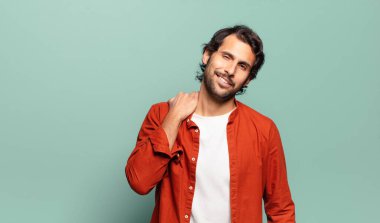 Genç, yakışıklı Hintli bir adam neşeli ve kendinden emin bir şekilde gülüyor.