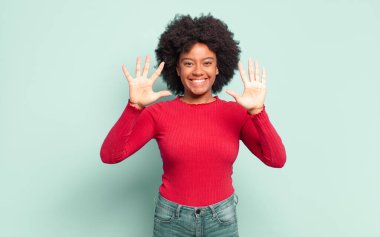  Gülümsüyor ve dost canlısı görünüyor, onuncu ya da onuncu numarayı gösteriyor, eli önde, geri sayıyor.