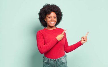  Gülümseyen ve her iki elinle yukarı ve yana doğru gösteren nesne kopyalama boşluğunda