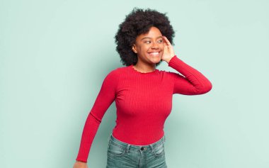  Gülümsüyor, tuhaf bir şekilde yan tarafa bakıyor, dedikoduları dinlemeye ya da bir sırrı duymaya çalışıyor.