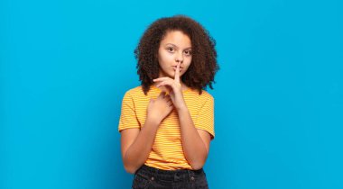  Ciddi görünüyor ve parmaklarını dudaklarına bastırıyor sessizlik ya da sessizlik talep ediyor, sır saklıyor.