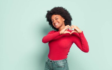  Gülümsüyor ve mutlu hissediyorum, sevimli, romantik ve aşık, her iki elinle kalbi şekillendiriyor.