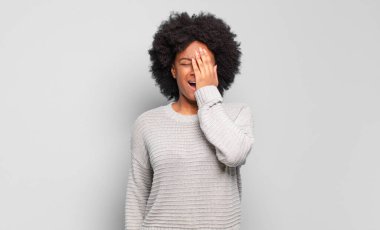  Uykulu görünüyor, sıkılmış ve esniyor, baş ağrısı ve yüzünün yarısını kaplayan bir elle.