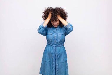 Kadın kendini stresli ve hayal kırıklığına uğramış hissediyor, el ele tutuşuyor, yorgun, mutsuz ve migren ağrısı çekiyor.