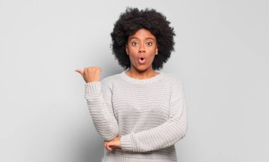  İnançsızlıktan şaşkın şaşkın bakıyor, yan taraftaki objeyi işaret ediyor ve 