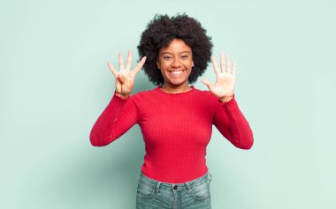  Gülümsüyor ve dost canlısı görünüyor, 9 ya da 9 numarayı gösteriyor, eli önde, geri sayıyor.