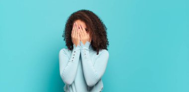  Yüzü ellerle kaplamak, parmaklarının arasından bakmak şaşırmış bir ifadeyle yan tarafa bakmak.