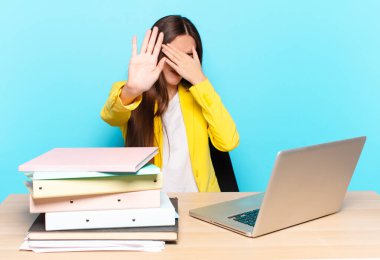 Genç, güzel bir iş kadını yüzünü elleriyle kapatıyor ve kamerayı durdurmak için diğer elini öne koyuyor. Fotoğraf ya da resimleri reddediyor.