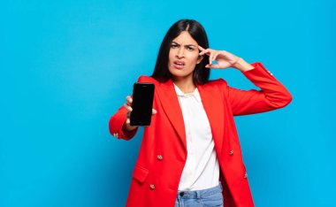 Genç İspanyol kadın şaşkın ve şaşkın hissediyor. Deli, deli ya da aklını kaçırmış olduğunu gösteriyor. telefon ekran kopyalama alanı