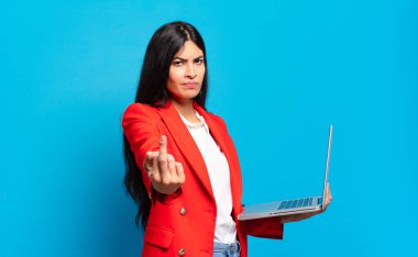 Genç İspanyol kadın kızgın, sinirli, isyankar ve agresif hissediyor, orta parmağını sallıyor, karşı koyuyor. dizüstü bilgisayar