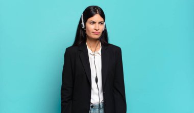 Genç İspanyol tele pazarlamacı kadın üzgün, üzgün ya da kızgın hissediyor ve olumsuz bir tavır takınıyor, anlaşmazlık içinde kaşlarını çatıyor.