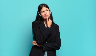 Genç İspanyol pazarlamacı kadın düşünüyor, kuşkulu ve şaşkın hissediyor, farklı seçeneklerle, hangi kararı vereceğini merak ediyor.