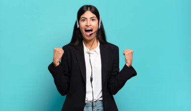 Genç İspanyol pazarlamacı kadın kızgın bir ifadeyle agresif bağırıyor ya da yumruklarıyla başarıyı kutluyor.