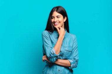 Genç Latin asıllı sıradan bir kadın mutlu ve kendinden emin bir ifadeyle gülümsüyor.