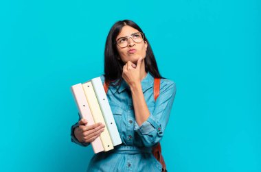 Genç İspanyol öğrenci kadın düşünüyor, kuşkulu ve şaşkın hissediyor, farklı seçeneklerle, hangi kararı vereceğini merak ediyor.