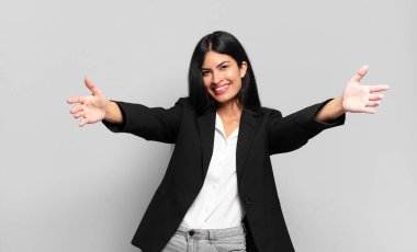 Genç İspanyol iş kadını neşeyle gülümsüyor sıcak, dostça, sevgi dolu bir kucak veriyor, mutlu ve sevimli hissediyor.