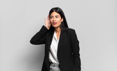 Genç İspanyol iş kadını gülümsüyor, tuhaf bir şekilde yan tarafa bakıyor, bir dedikoduyu dinlemeye çalışıyor ya da bir sırrı duymaya çalışıyor.