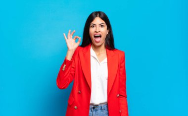 Genç İspanyol iş kadını kendini başarılı ve tatmin olmuş hissediyor, ağzı açık gülümsüyor, elle imza atıyor.