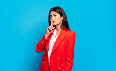 Genç İspanyol iş kadını sessizlik ve sessizlik istiyor, parmağıyla ağzının önünde işaret ediyor, 