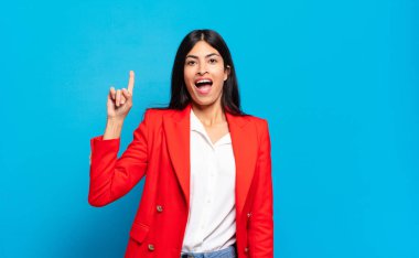 Genç İspanyol iş kadını bir fikri fark ettikten sonra mutlu ve heyecanlı bir dahi gibi hissediyor, neşeli bir şekilde parmağını kaldırıyor, eureka!