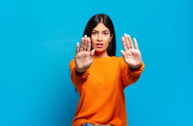 Genç ve güzel İspanyol bir kadın ciddi, mutsuz, kızgın ve hoşnutsuz görünüyor. Girmeyi yasaklıyor ya da her iki avuçta da dur diyor.