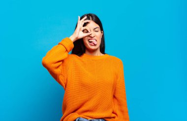 Genç ve güzel İspanyol kadın mutlu bir şekilde gülümsüyor, şaka yapıyor ve gözetleme deliğinden bakıyor, sırları gözetliyor.