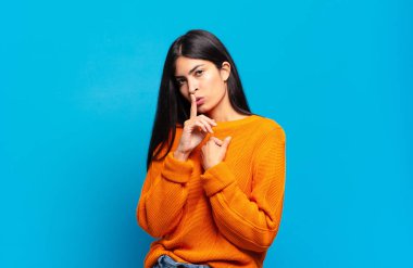 Genç ve güzel İspanyol kadın ciddi görünüyor ve parmaklarını dudaklarına bastırıp sessizlik ya da sessizlik talep ediyor, sır saklıyor.