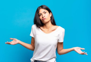 young pretty hispanic woman feeling clueless and confused, having no idea, absolutely puzzled with a dumb or foolish look