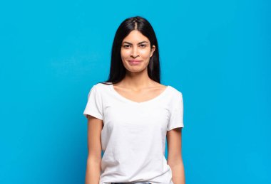 Genç, güzel İspanyol kadın pozitif ve kendinden emin gülümsüyor. Tatmin olmuş, arkadaş canlısı ve mutlu görünüyor.