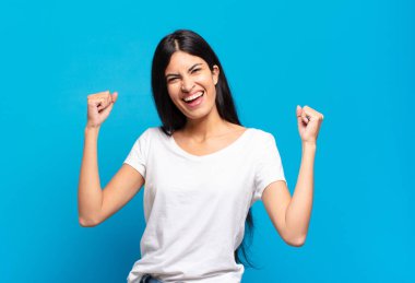 Genç, güzel, İspanyol bir kadın muzaffer bir şekilde bağırıyor. Heyecanlı, mutlu ve şaşkın bir kazanan gibi görünüyor.