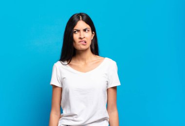 Genç ve güzel İspanyol kadın kafası karışmış görünüyor, merak ediyor ya da bir sorunu çözmeye çalışıyor ya da düşünüyor.