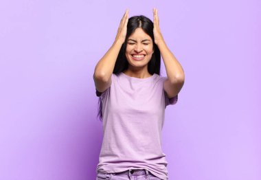 Genç ve güzel İspanyol kadın stresli ve endişeli hissediyor, bunalımda ve hayal kırıklığına uğramış, iki elini de başa kaldırıyor.