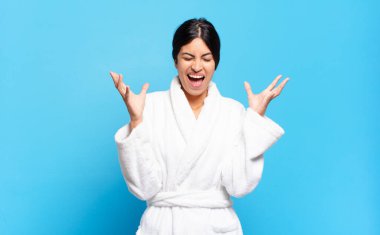 Genç İspanyol kadın öfkeyle bağırıyor, stresli hissediyor ve ellerini havaya kaldırıp neden ben diye bağırıyor. Bornoz konsepti