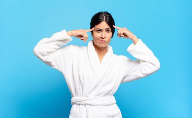 Ciddi ve konsantre görünümlü, beyin fırtınası yapan ve zorlu bir sorunu düşünen genç bir İspanyol kadın. Bornoz konsepti