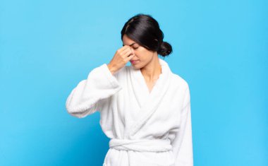 Genç İspanyol kadın stresli, mutsuz ve hayal kırıklığına uğramış, alınına dokunmuş ve şiddetli baş ağrısı çeken. Bornoz konsepti