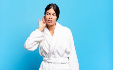 Genç İspanyol kadın ciddi ve meraklı görünüyor, dinliyor, gizli bir konuşma veya dedikodu duymaya çalışıyor, kulak misafiri oluyor. Bornoz konsepti