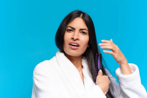 young hispanic woman with a hair brush.